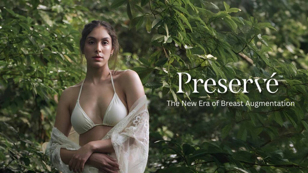 Model in a white bikini showcasing Motiva Preservé breast augmentation, surrounded by lush greenery, emphasizing natural aesthetics and beauty.