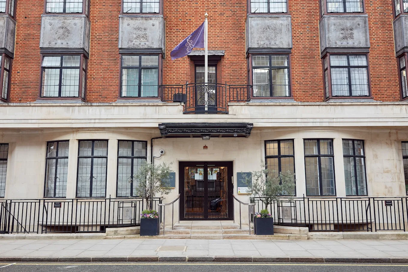 King Edward VII's Hospital entrance featuring elegant architecture, welcoming steps, and a flag, situated in London, UK, highlighting Lux Plastic Surgery's commitment to quality patient care.